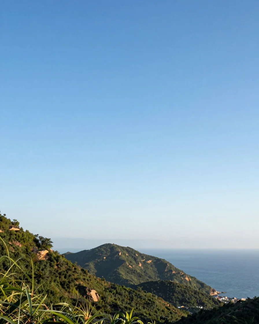 Wide editorial travel photograph of a coastal mountain landscape at golden hour, clear natural daylight, vivid destinati